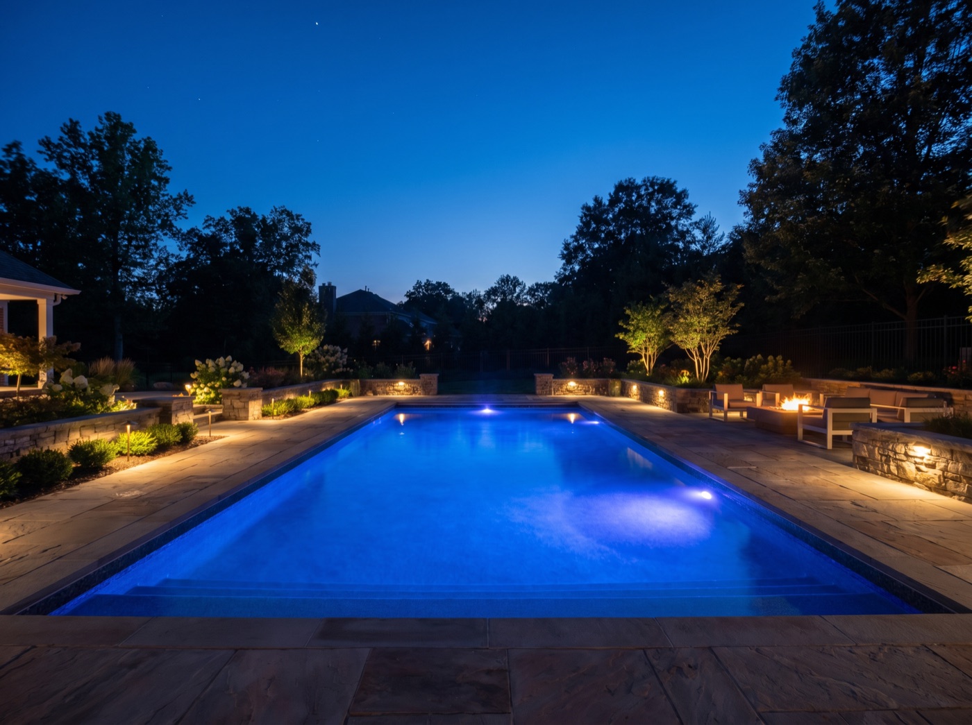 A backyard pool glowing blue at twilight